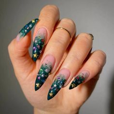 a woman's hand with green and gold nail designs on her nails, which are decorated with stars