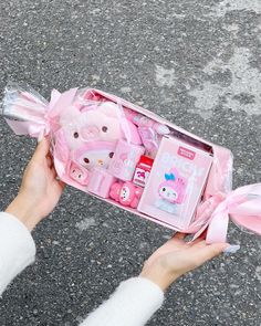 a person holding a pink hello kitty toy in a box with its contents wrapped around it