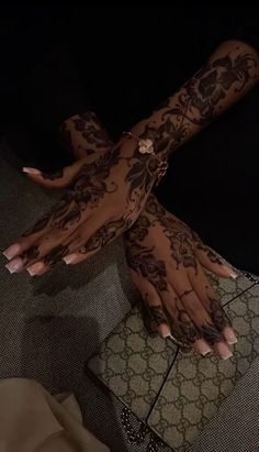 a woman's hands covered in hennap and tattoos on her left arm