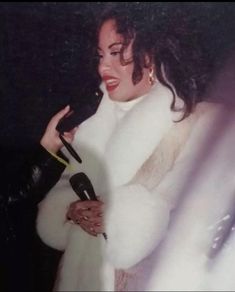 a woman in a fur coat holding a microphone