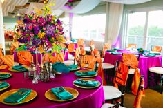 the table is set with purple, yellow and green place settings for an elegant dinner