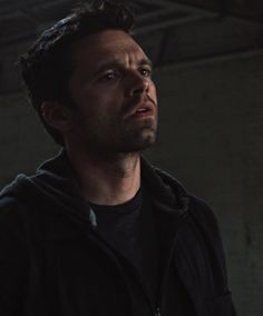 a man in a black hoodie looking off into the distance