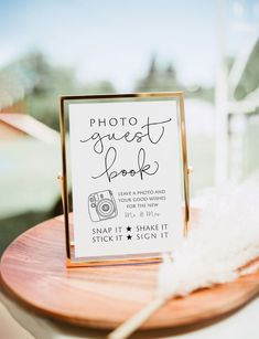 a photo guest book sitting on top of a wooden table next to a white feather