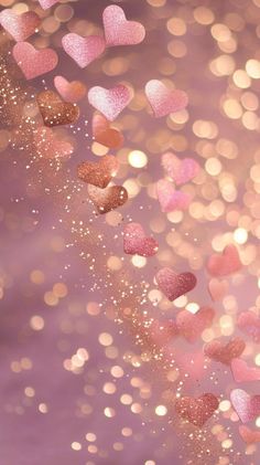 pink and gold hearts are flying in the air with sparkles all around them on a purple background