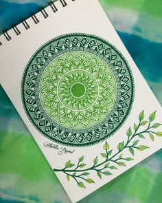 a spiral notebook with a green and white design on the cover, next to a pen