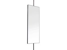 a tall mirror on a stand with a black metal pole and white wall behind it