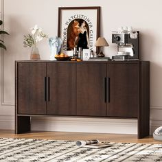 a sideboard with pictures and other items on it in a room next to a rug