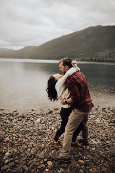 a man carrying a woman on his back by the water