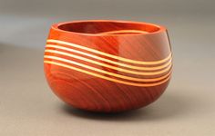 a wooden bowl sitting on top of a table next to a gray wall and floor