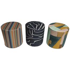 three different colored stools sitting next to each other on a white surface, one with an abstract design