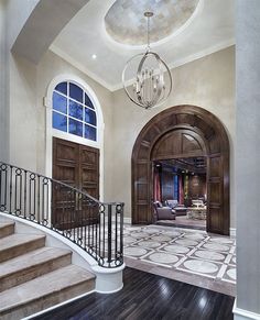 a foyer with stairs, chandelier and large windows