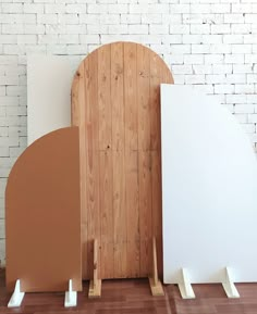 three pieces of wood sitting on top of a hard wood floor next to a white brick wall