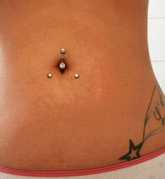 a woman's stomach with two piercings on the side and one in the middle