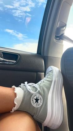 a person's feet in the passenger seat of a car, wearing converse sneakers