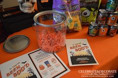 an orange table topped with lots of halloween treats and candy bar wrappers next to it