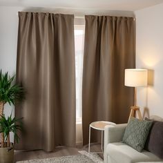 a living room with a couch, chair and window covered in brown drapes