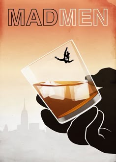 a hand holding a glass with an image of a man on it and the words mad men above it