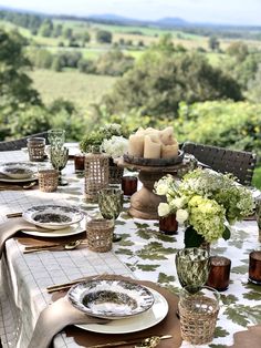 an outdoor table set with plates and place settings