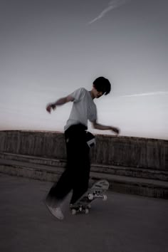 a young man riding a skateboard on top of a cement wall next to a sidewalk