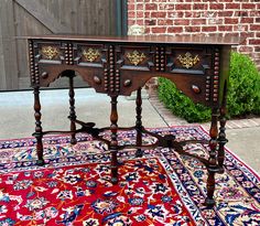 an old wooden table on a rug in front of a brick wall