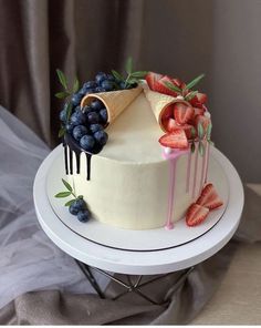 a cake decorated with strawberries, blueberries and an ice cream cone on top