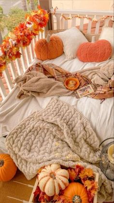 a bed covered in blankets and pumpkins on top of a wooden floor next to flowers