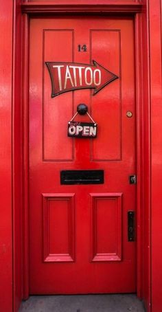 a red door with a sign that says tattoo on it and an arrow pointing to the right