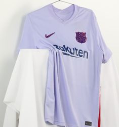 a soccer jersey hanging on a hanger next to two white and one red shirts