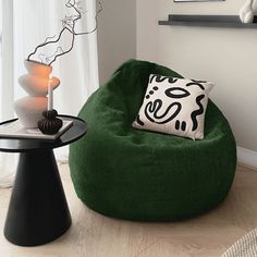 a green bean bag chair sitting on top of a wooden floor next to a table