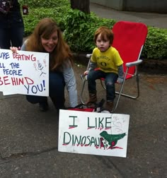 two children sitting in lawn chairs with signs on the ground and one holding a sign that says i like dinosaurs