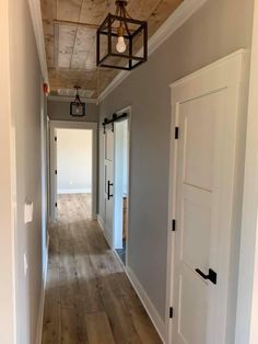 an empty hallway with white doors and wood flooring is seen in this image from the front door