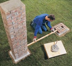 a man laying on the ground next to a brick wall with a shovel in it