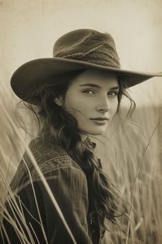 a woman wearing a hat is standing in tall grass with her head turned to the side