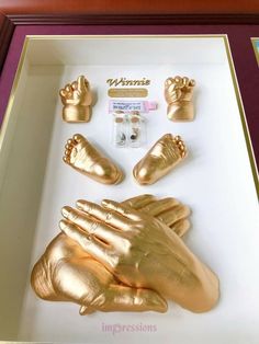 gold hand and foot casts in a shadow box