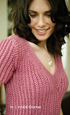 a close up of a person wearing a pink sweater and smiling at the camera with her hand on her hip