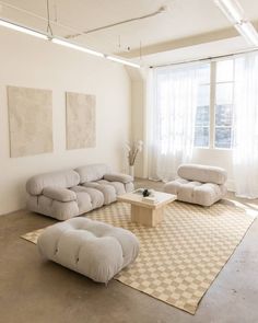 a living room filled with furniture and a large white rug on top of a hard wood floor