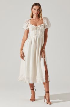 Puff sleeve midi dress Pleated bust with underwire Sweetheart neckline with ruffle and tie detail Left leg slit to above knee Concealed zipper at side seam Smocked back panel Fully lined, except sleeves Self: 81% Tencel, 19% Nylon / Lining: 100% Polyester Dry clean only Style #ACDR102144S Backless White Midi Dress, Neutral Long Sleeve Dress, Formal Wedding Guest Dress With Sleeves, Dresses With Bows On Shoulder, Winter Engagement Party Dress, Italian Women’s Fashion, Smocked Midi Dress, Country Reception Dress, White Garden Party Dress