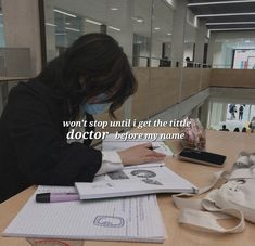 a woman sitting at a table with a book and cell phone in front of her