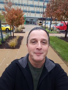 a man is taking a selfie in front of a parking lot with parked cars