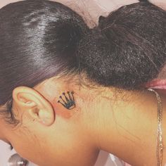 the back of a woman's head with a crown tattoo on her left ear