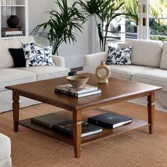 a living room with white couches and wooden coffee table in front of large windows