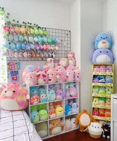 a room filled with lots of stuffed animals on shelves next to a bed and window