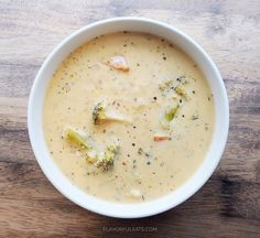 a white bowl filled with broccoli soup on top of a wooden table