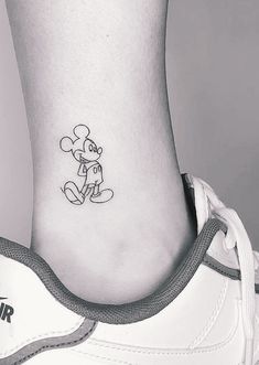 a small tattoo on the ankle of a person with a mickey mouse character in it