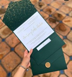 a person holding up a green envelope with a gold seal