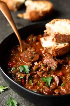 a bowl filled with meat and beans next to bread