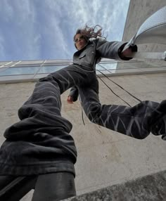 a man in black jacket standing on top of a cement wall next to a tall building