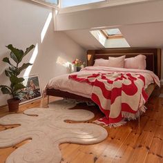 a bedroom with a bed, rugs and potted plant in the window sill