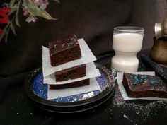 three pieces of chocolate cake on plates next to a glass of milk