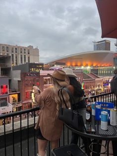 two people standing on a balcony looking at the city